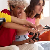 Deux amis jouant à une console dans un salon. Consoles en paiement mensuel avec Leasi.