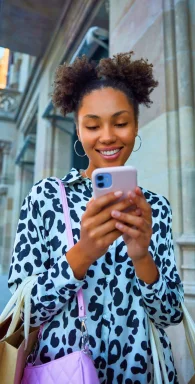 Femme souriante tenant un smartphone. Smartphones récents avec paiements mensuels adaptés.