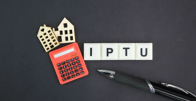 calculadora, ficha de casa e caneta com as letras IPTU ou a palavra Imposto sobre a propriedade predial e territorial urbana