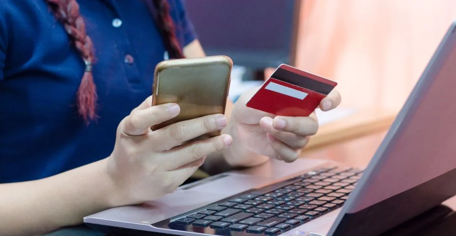 Mãos de mulher segurando um cartão de crédito usando no laptop e telefone inteligente. conceito de compra on-line. Pagamento on-line