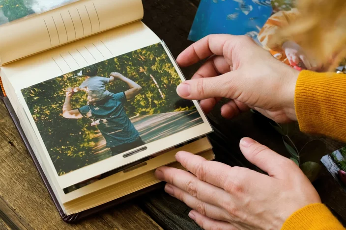 Conceito de impressão de fotos. Mãos femininas adicionando foto impressa ao álbum de imagens.