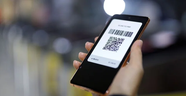 Uma jovem asiática paga rapidamente seu bilhete de metrô via smartphone na estação de metrô usando a tecnologia NFC sem contato ('tap and go')