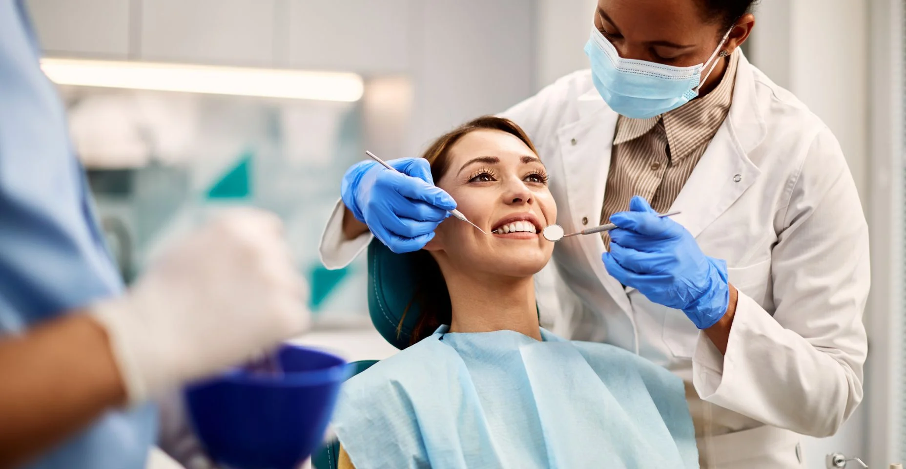 Jovem sorridente fazendo exame dentário no consultório do dentista.