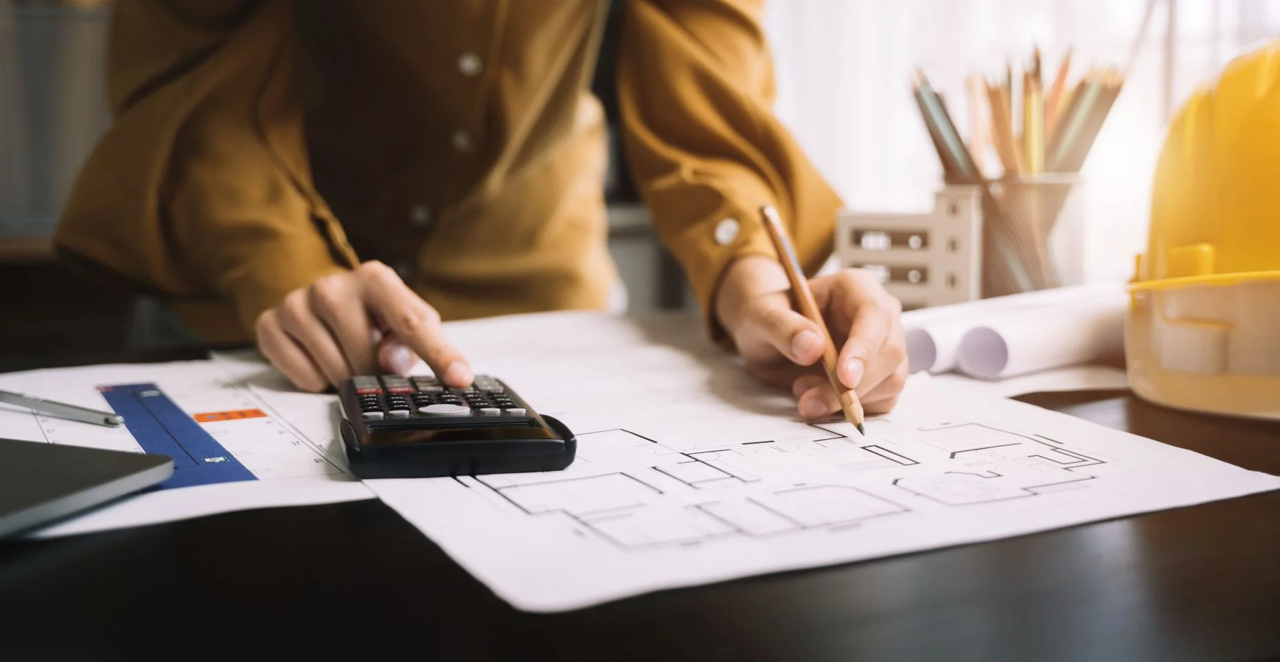 engenheiro civil ou arquiteto usando calculadora para calcular o custo para trabalhar no projeto de design do plano de construção no escritório.
