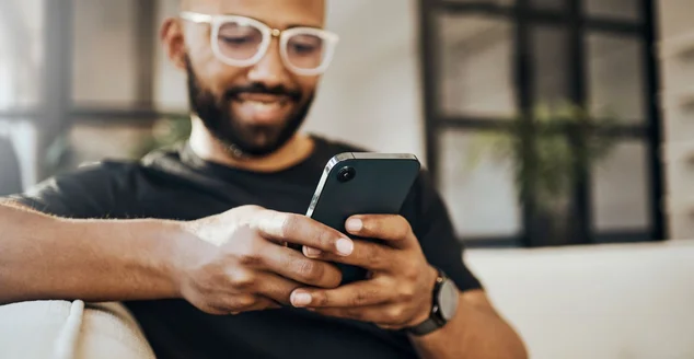 Homem feliz, telefone de mídia social e sala de estar relaxam, digitando smartphone e comunicação online, lendo notificação e web no sofá. Mãos de cara sorriso, conexão móvel e tecnologia de rede doméstica