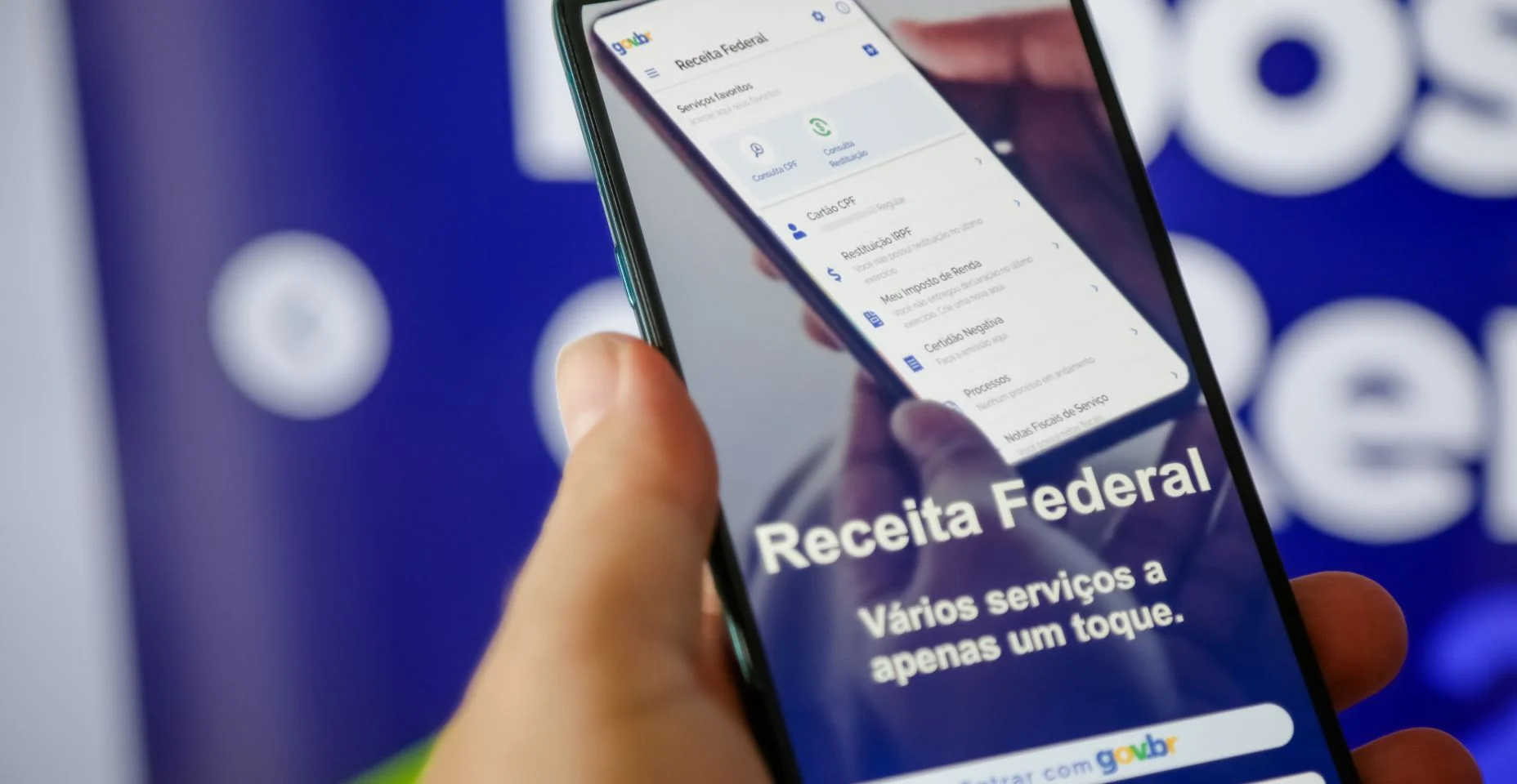 Imposto de renda 2024 da receita federal segurando celular com aplicativo e dinheiro