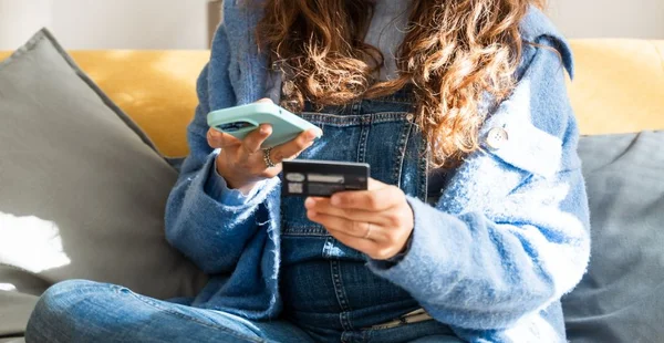 Mulher que faz compras on-line usando smartphone e cartão de crédito