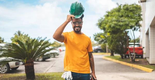 Homem negro usando camiseta amarela e capacete de EPI verde