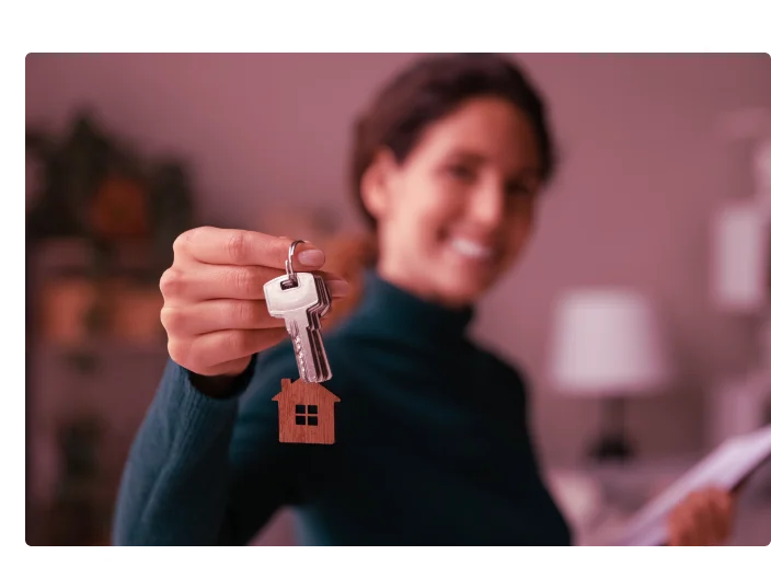 mulher sorrindo com chave de casa na mão