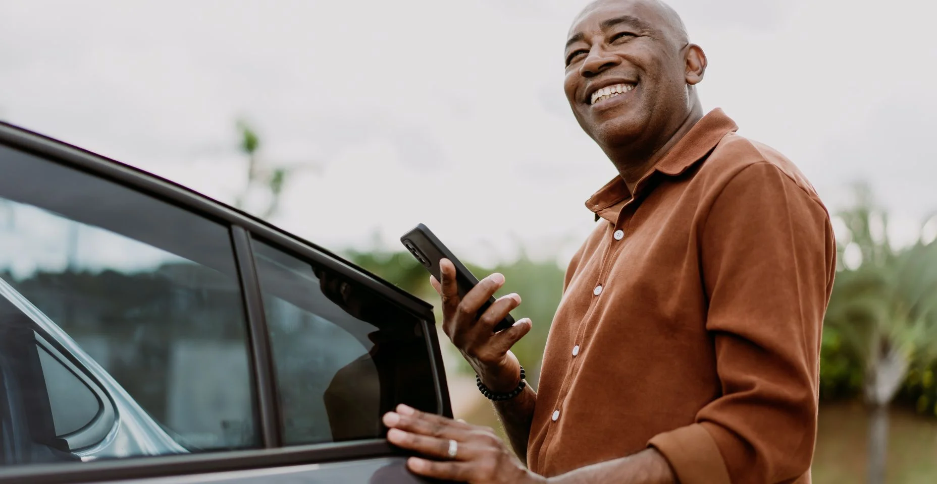 Homem entrando no carro segurando smartphone