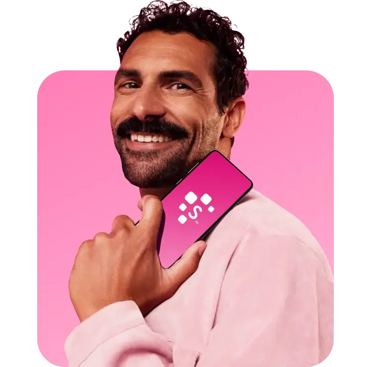 Homem negro sorrindo, vestindo uma blusa rosa e segurando o celular na mão com aplicativo Serasa