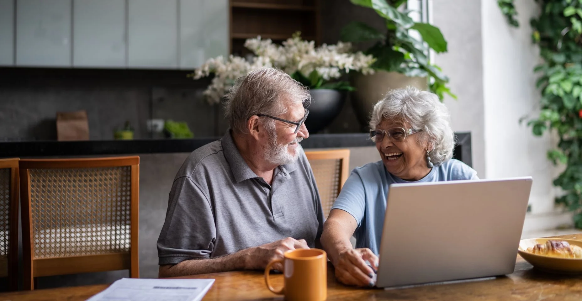 Casal de idosos falando sobre finanças domésticas e usando o laptop em casa