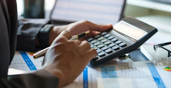 Contador focado trabalhando usando calculadora para cálculo de finanças, impostos e estatísticas.