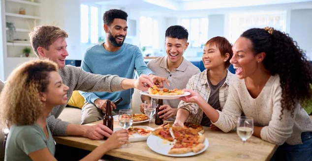 Amigos se divertindo em casa na cozinha comendo pizzas caseiras