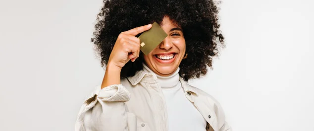 Mulher jovem feliz segurando um cartão de crédito sobre seu olho