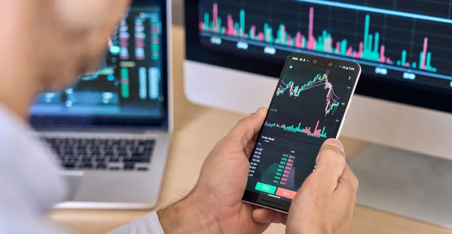 Corretor de traders de criptomoedas usando aplicativo de telefone analisando mercado de ações no celular.