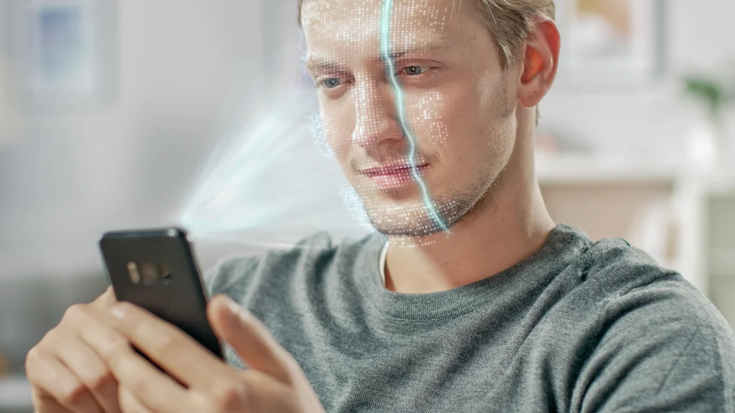 Homem jovem identificado pelo processo de digitalização de reconhecimento facial biométrico de seu smartphone. Conceito futurista: o projetor identifica o indivíduo iluminando a cara por pontos e a exploração com laser