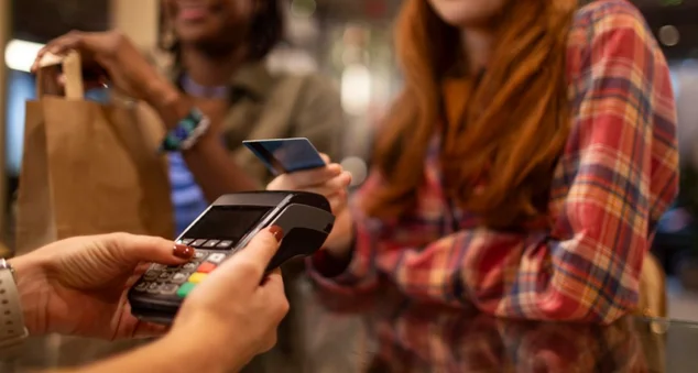 Mulher pagando uma compra com a aproximação do cartão de crédito