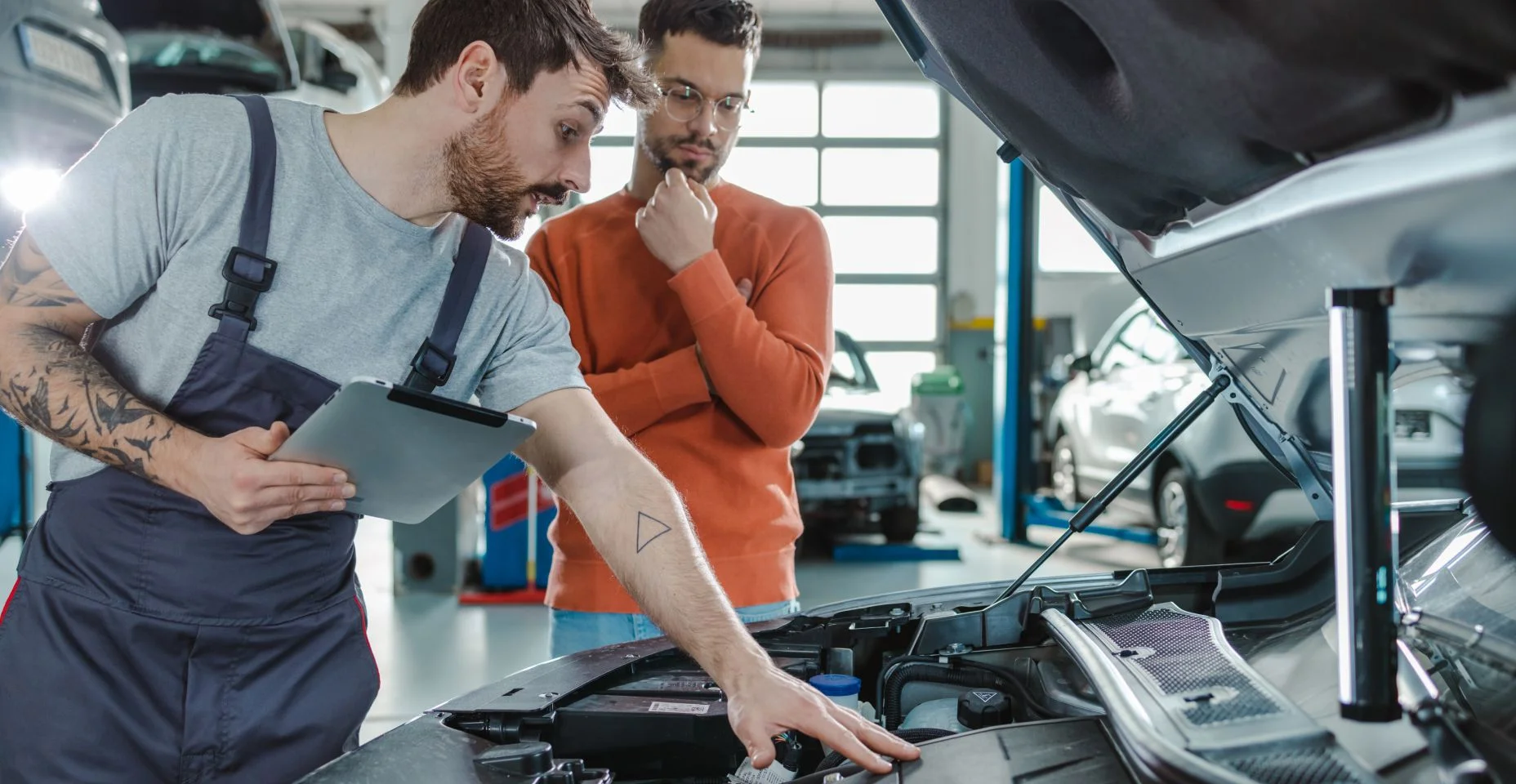 Cliente e técnico automotivo falando sobre o problema do carro em uma oficina -