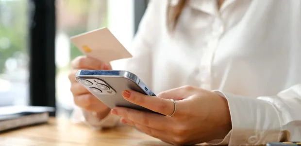 Mão segurando um IPhone e um pedaço de papel