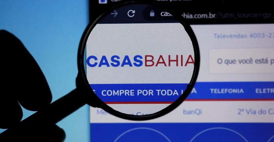 Homepage do Site Casas Bahia ampliado em logotipo com lupa. Logotipo Casas Bahia. Empresa brasileira.