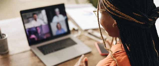 Mulher afro descendente participando de uma reunião virtual em sua mesa em casa