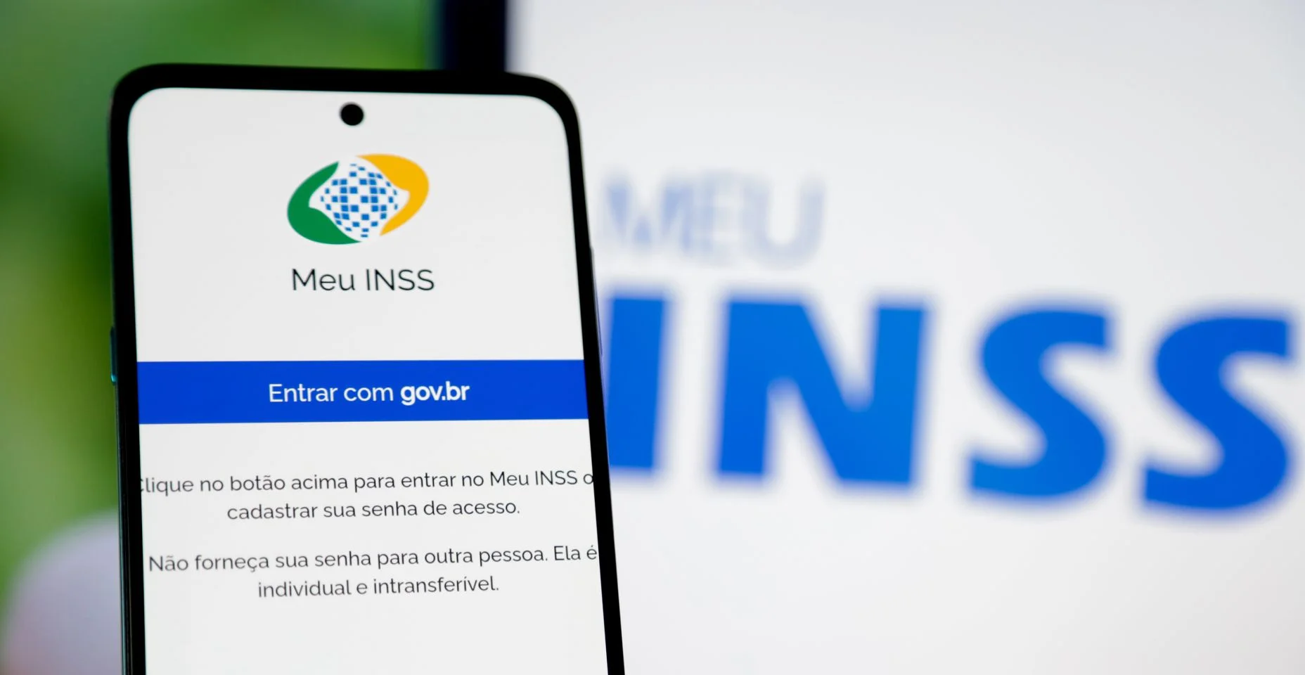 Aplicativo INSS do governo para aposentados no Brasil, na tela de um celular e fundo desfocado.