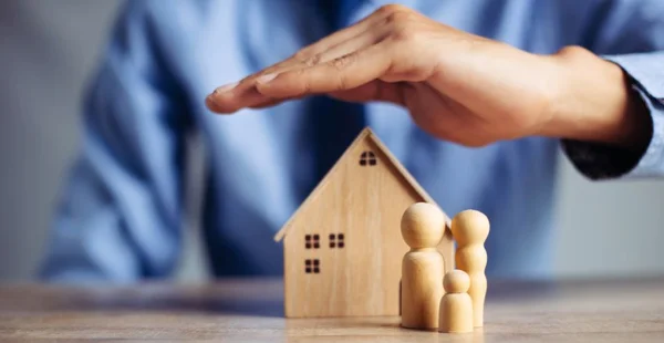 A seguradora e o conceito de vida da saúde da família. O agente de seguros apresenta o modelo de proteção das mãos que simboliza a cobertura.