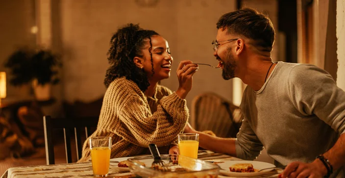 Casal dando comida um na boca do outro