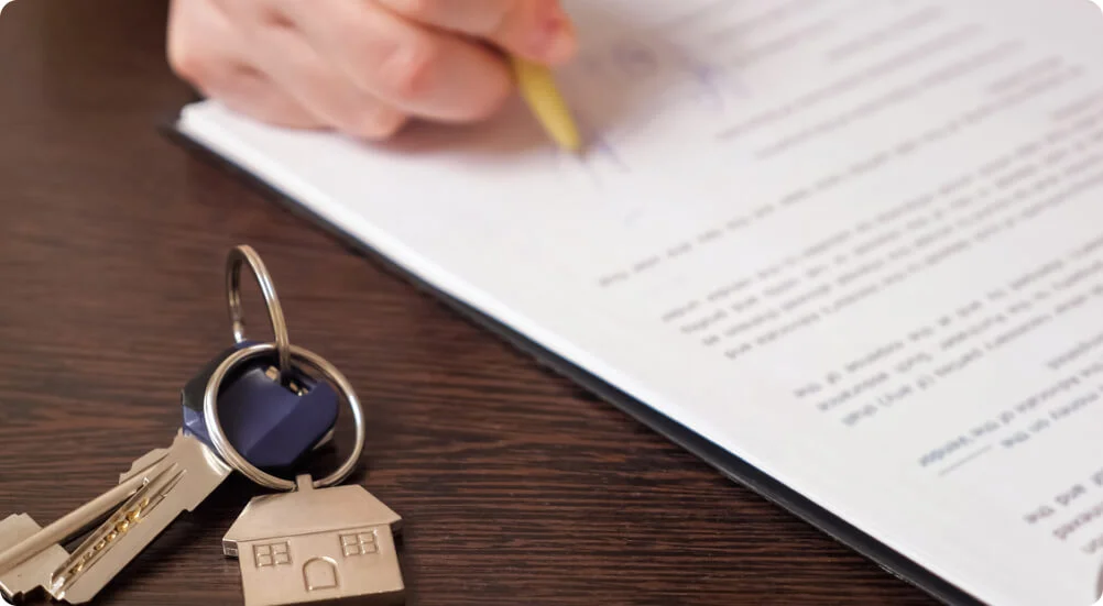 Homem assina contrato de compra de apartamento perto de chaves à mesa