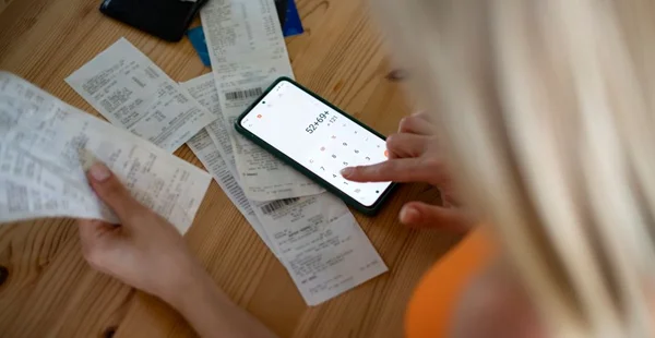 Mulher olhando para contas e verificando despesas com calculadora