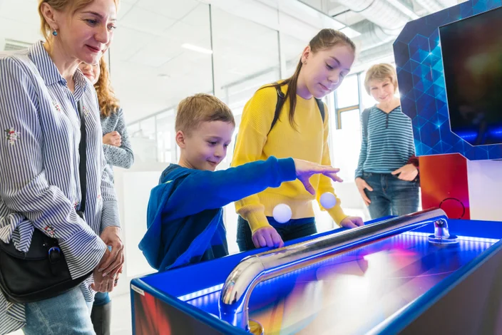 A família, crianças e adultos, tem um divertido quando eles explorando a exposição no Hall da ciência e tecnologia