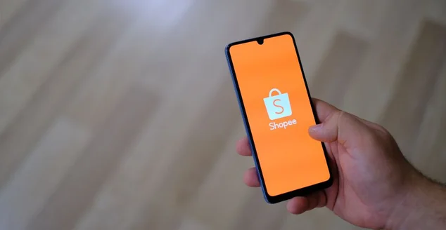 Uma pessoa segurando um smartphone e o logotipo do aplicativo Shopee na tela do telefone. Conceito de smartphone e aplicativo móvel. Logotipo do aplicativo Shopee em um smartphone