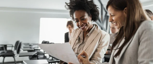 Mulheres no escritório olhando um papel no serviço para ilustrar artigo sobre dia do trabalhador