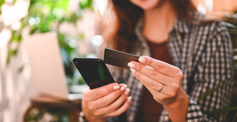 Close up da mão da mulher usando cartão de crédito ao pagar contactless pelo telefone celular.