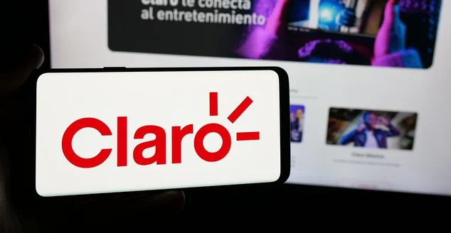 Pessoa segurando um smartphone com o logotipo da empresa de telecomunicações Claro Equador na tela, em frente ao site. Foco na tela do celular.