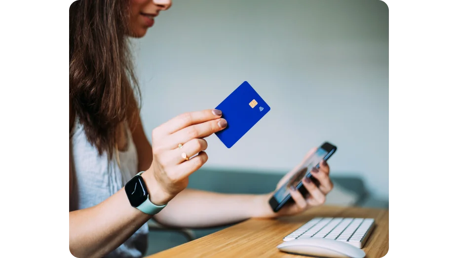 Mulher segurando o cartão e olhando para o celular