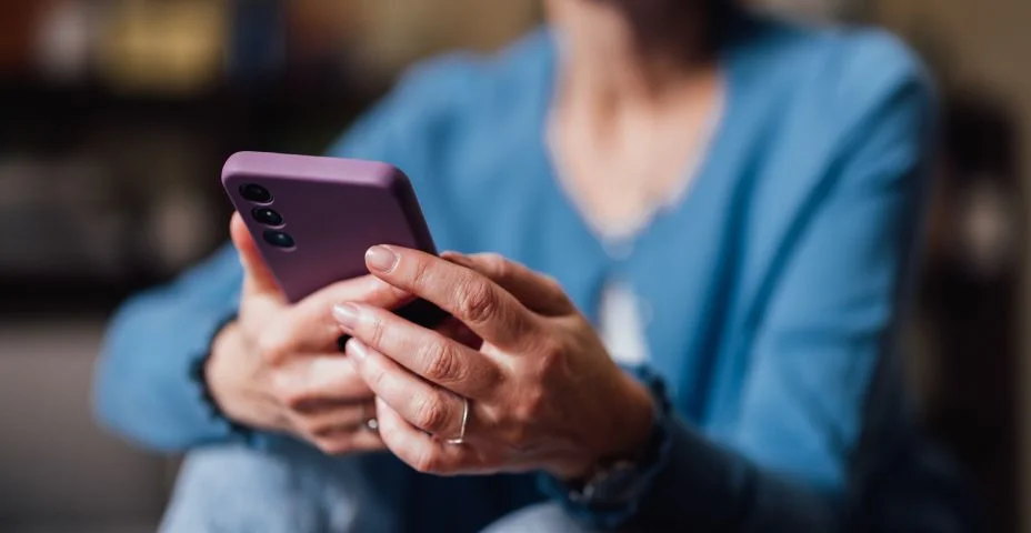 Mulher sênior usando o smartphone em ambiente casual, mãos de close-up