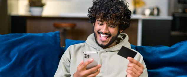 homem com cartão e celular na mão com uma cara de Feliz