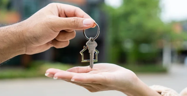 Mulher comprando ou alugando casa nova ela segurando chave na frente da casa nova. Surpresa jovem asiática feliz dando chave de casa e sorriso para alugar ou comprar casa de apartamento. Conceito de mudança de rumo.