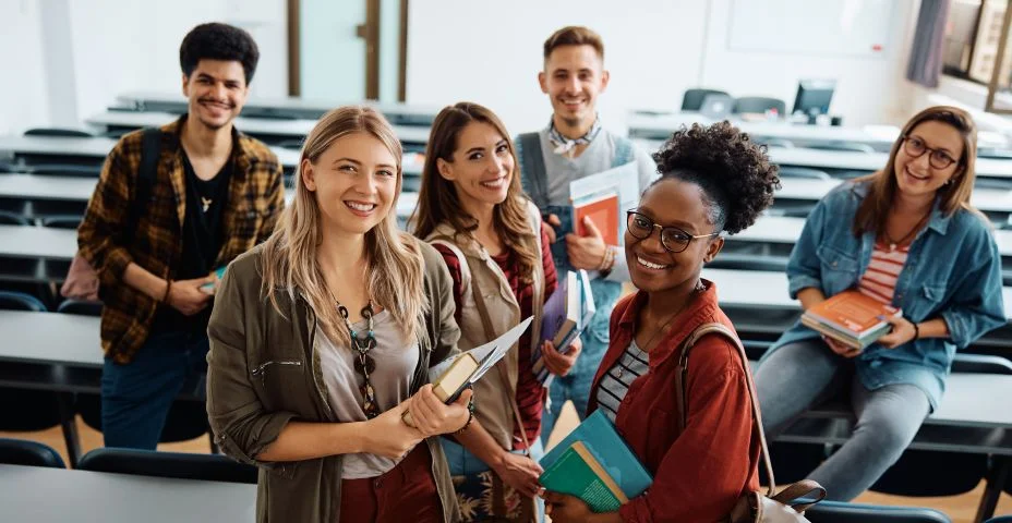 Grupo multirracial de alunos felizes na sala de aula olhando para a câmera.