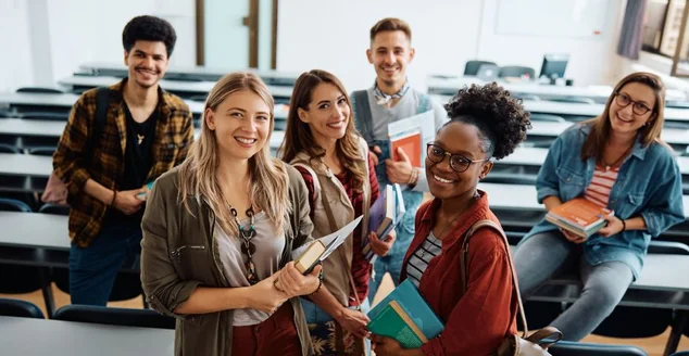 Grupo multirracial de alunos felizes na sala de aula olhando para a câmera.