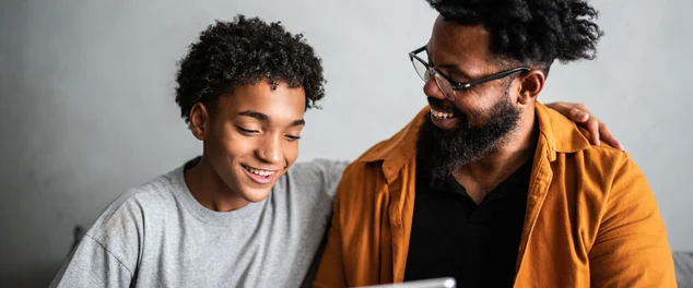 Pai e filho felizes usando tablet digital em casa