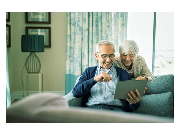 Casal de idosos sentandos e olhando para a tela de um tablet