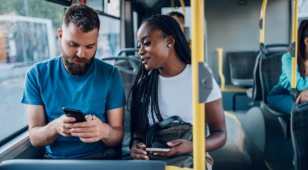 Amigos falando e usando um smartphone enquanto andam de ônibus na cidade