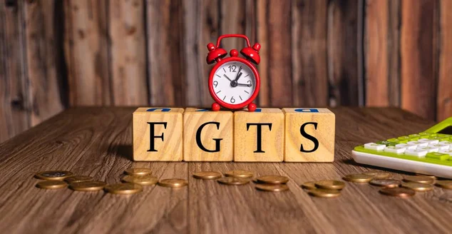 As iniciais FGTS de Fundo de Garantia do Tempo de Serviço com um relógio despertador, moedas e uma calculadora na composição.
