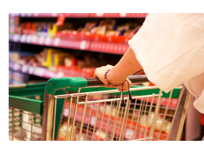 Jovem mulher no supermercado com o carrinho de compras