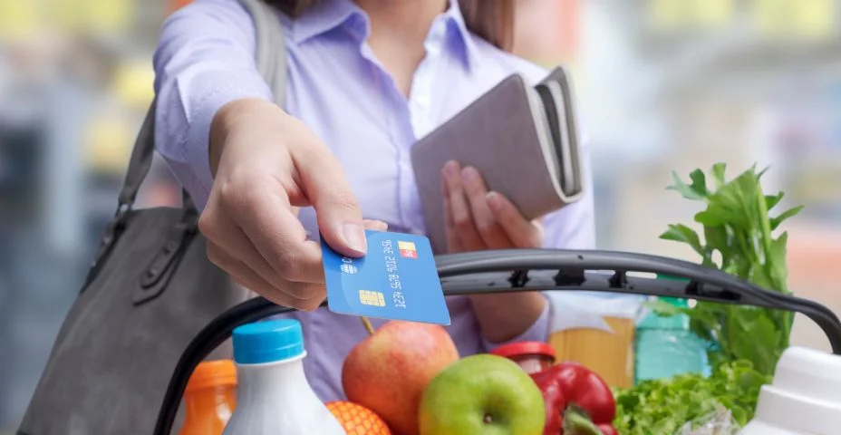 Mulher pagando por mantimentos usando um cartão de crédito