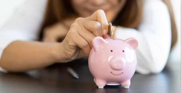 Mulher de perto colocando moeda em cofrinho. Conceito de economia de dinheiro.