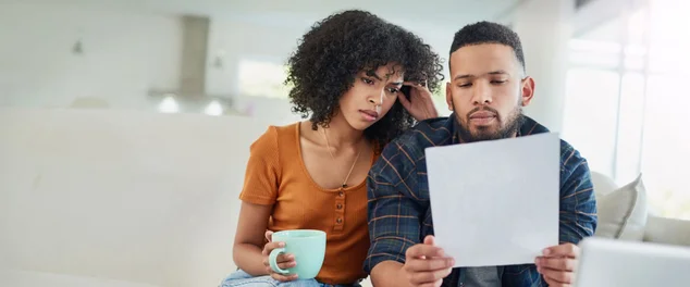 Casal juntos olhando um papel de dívida para ilustrar o artigo sobre as dívidas contraídas antes do casamento